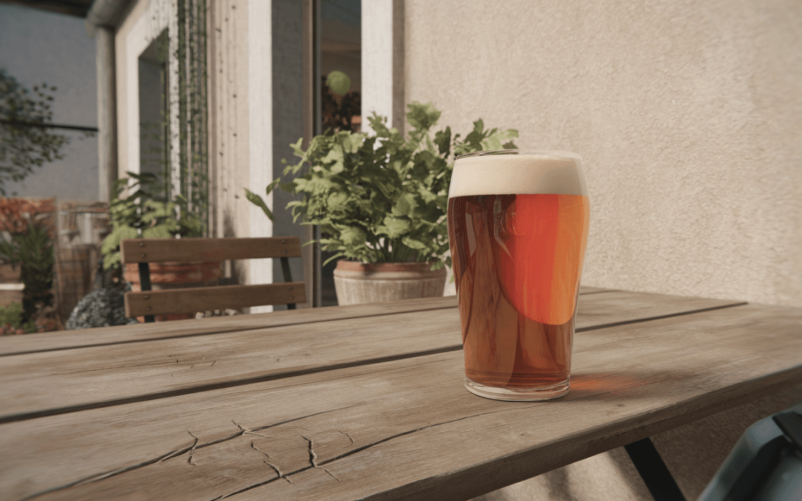 Un verre de bière brune avec mousse, posé sur une table en bois, entouré de plantes et d'une maison en arrière-plan.