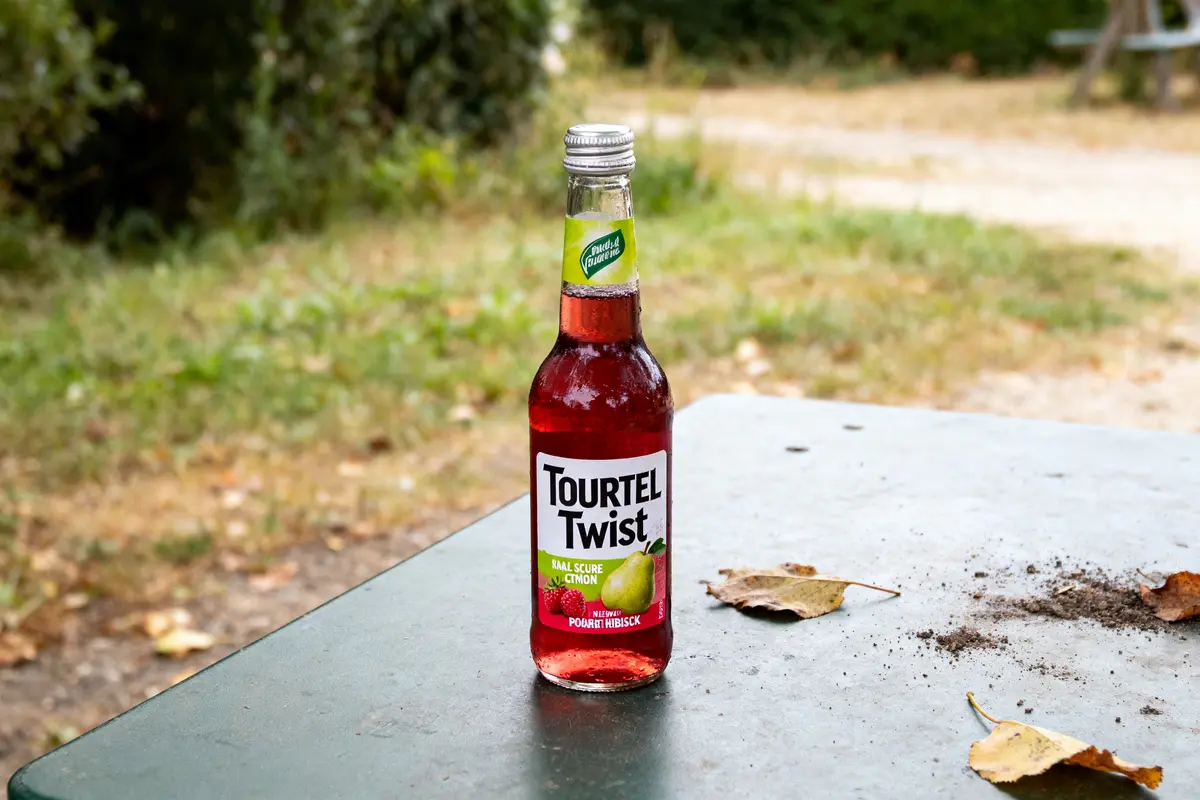 Bouteille de Tourtel Twist citron hibiscus sur une table extérieure avec feuilles mortes.