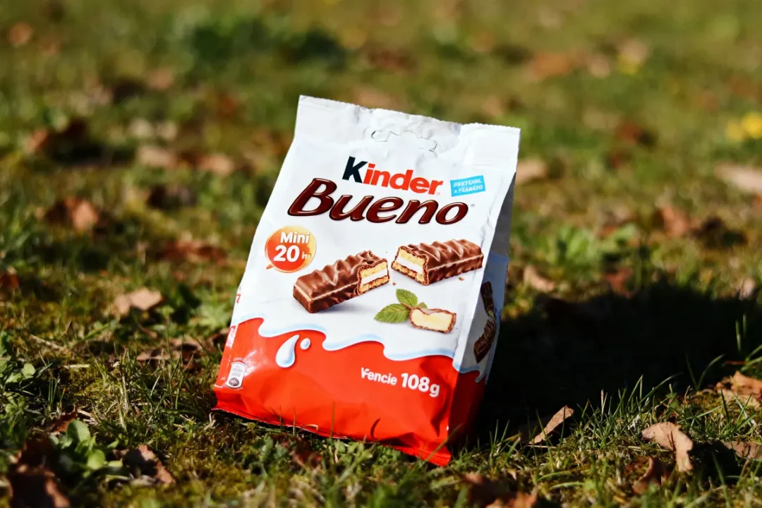 Paquet de Kinder Bueno Mini sur herbe, illustrant le produit chocolaté avec des noix.