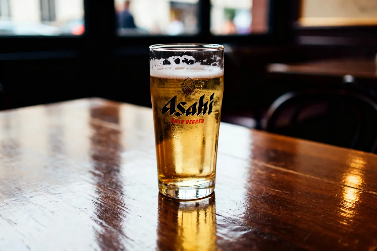 Verre de bière Asahi posé sur une table en bois dans un bar lumineux