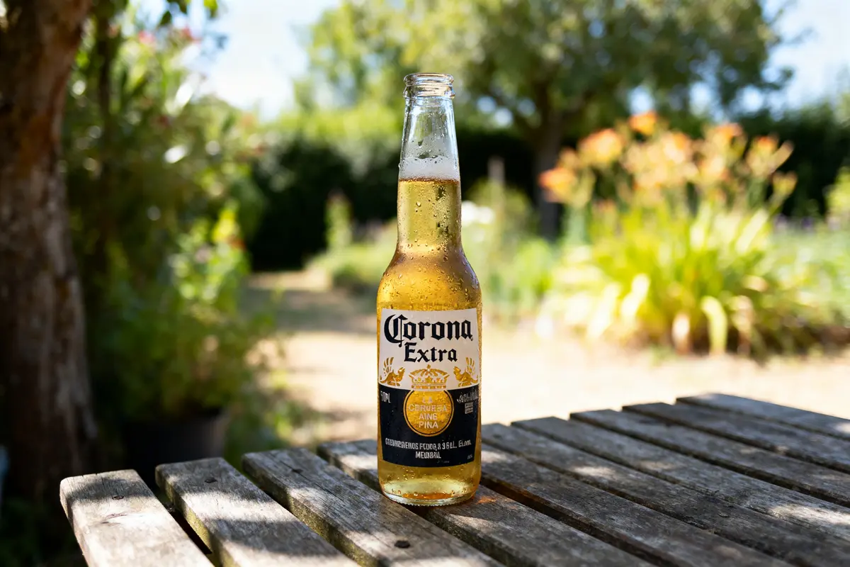 Bouteille de bière Corona Extra sur table en bois dans un jardin ensoleillé
