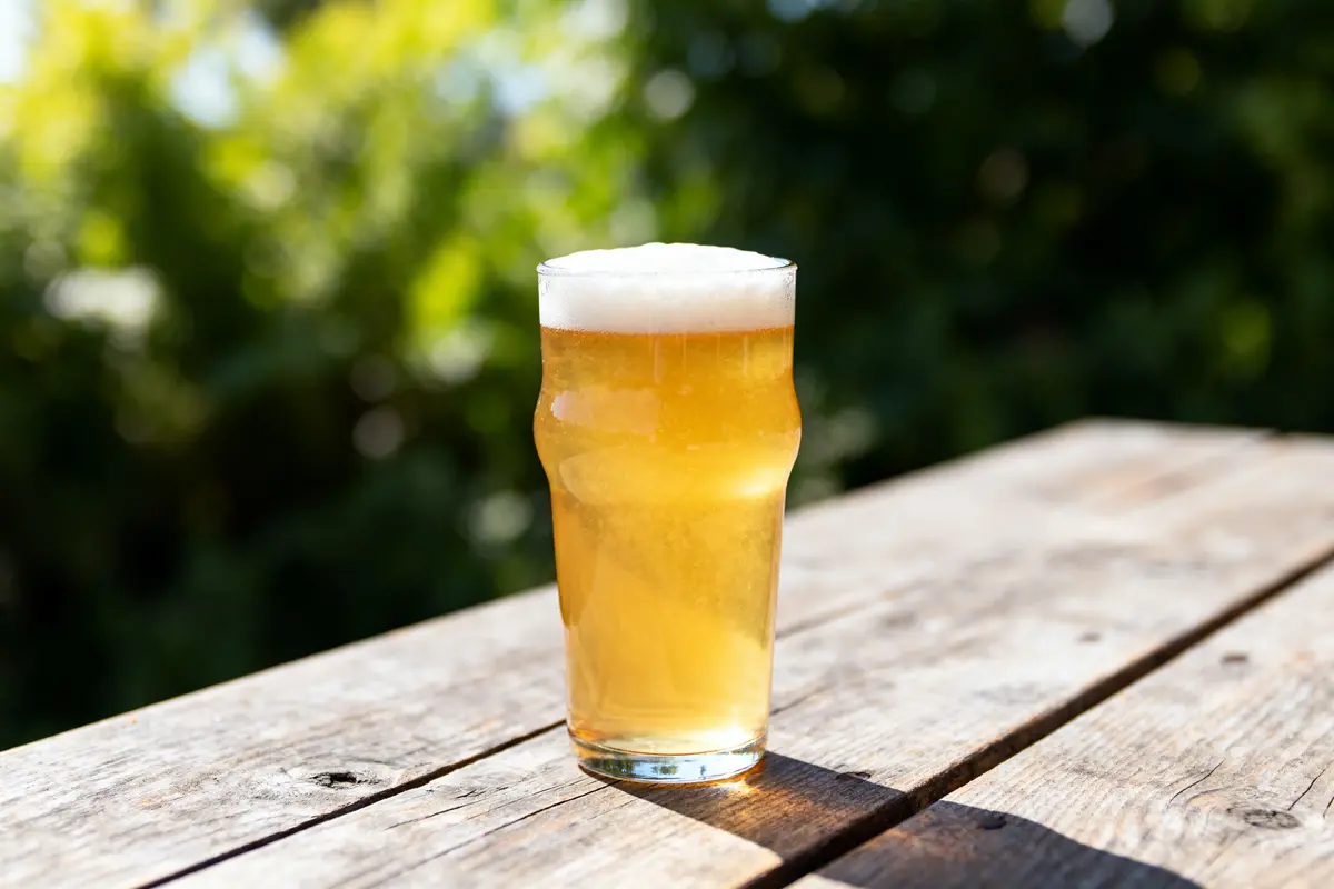 Verre de bière Gose dorée sur table en bois en extérieur lumineux