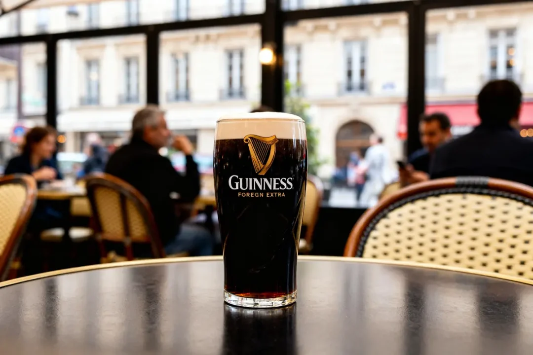 Verre de bière Guinness Foreign Extra posé sur une table dans un café parisien.