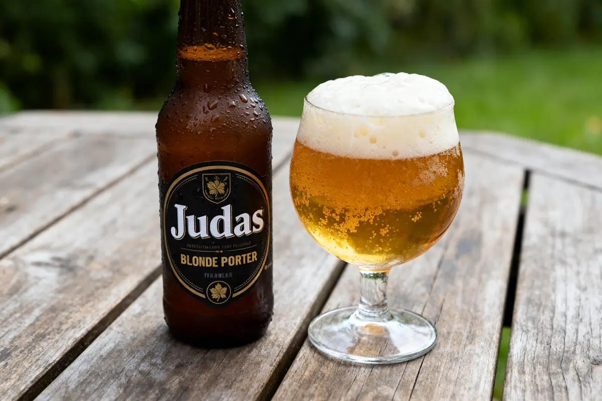 Bouteille et verre de bière Judas sur table en bois extérieur