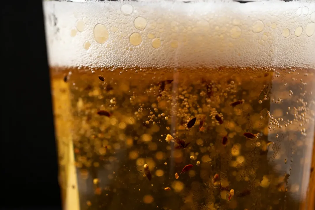 Verre rempli de bière non filtrée pétillante avec mousse épaisse et sédiments naturels