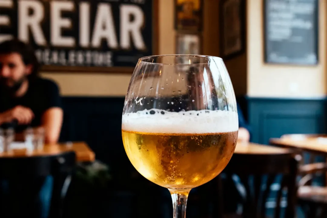 Verre de bière plein posé sur une table en bois dans un café. Arrière-plan flou.