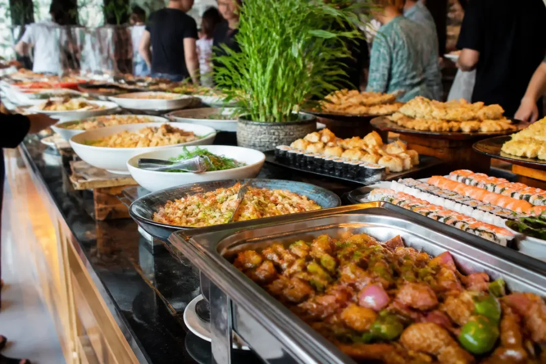 Buffet varié avec plats asiatiques, sushis, tempura, salades et décoration végétale, ambiance conviviale festive.